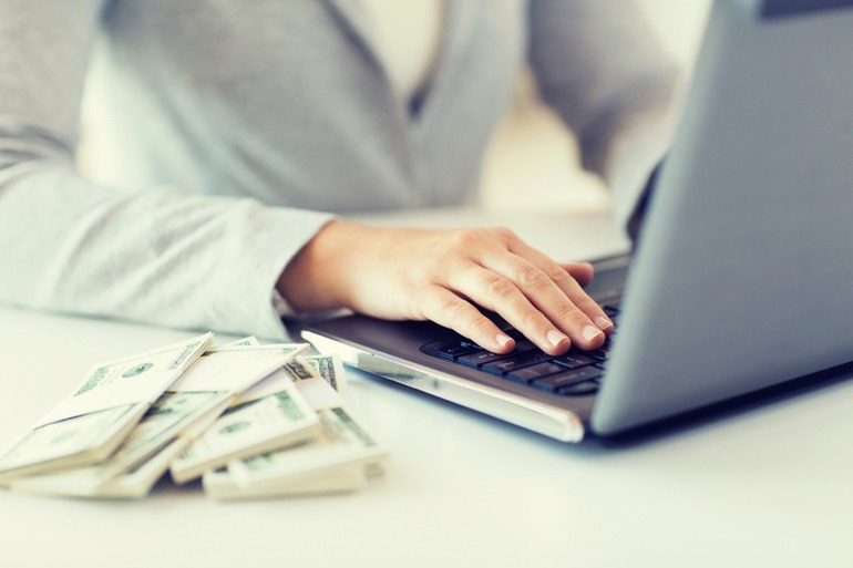 A hand on a computer keyboard, usd beside