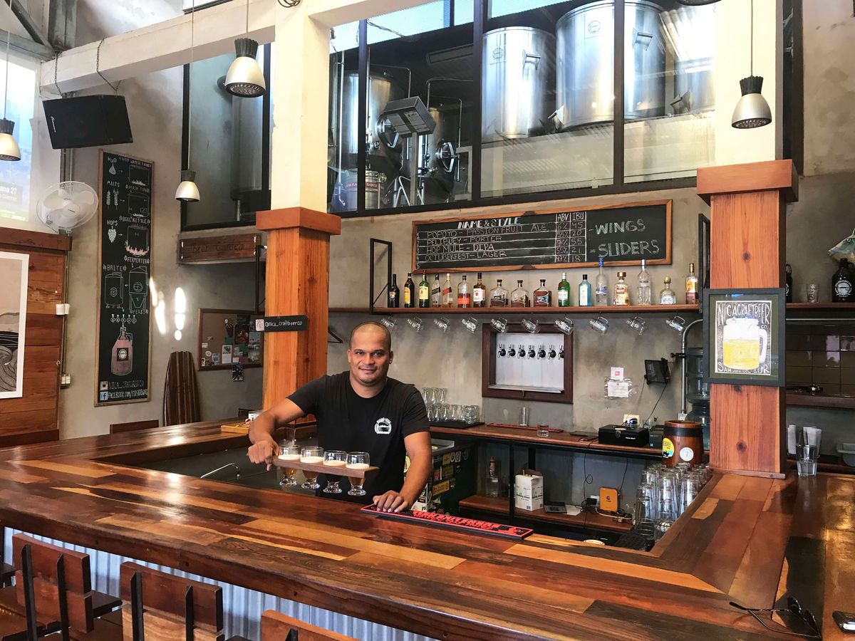 Bartender presenting a beer flight at the bar at Nicaragua Craft Beer Co.