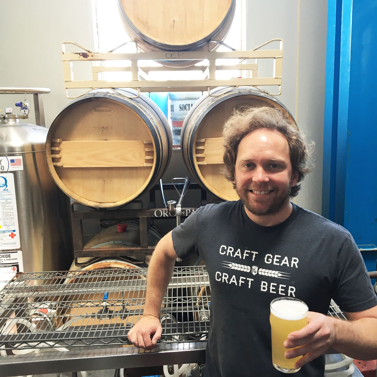 Brewery employee with Social Kitchen & Brewery posing with a glass of Tiple IPA.